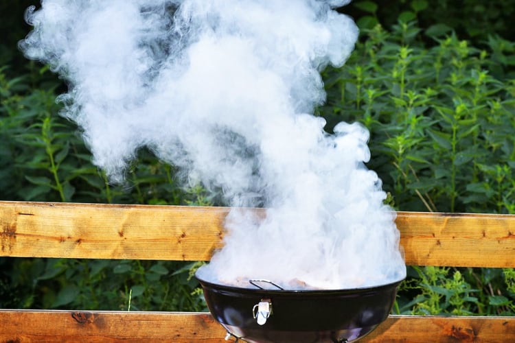 a barbecue creating smoke on a grill